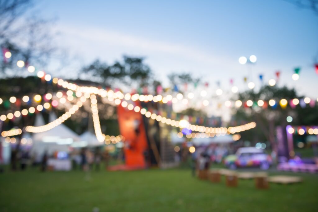 Outdoor celebration event at dusk with strings of overhead lights.